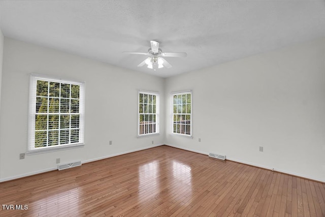 unfurnished room featuring hardwood / wood-style flooring, a ceiling fan, and visible vents