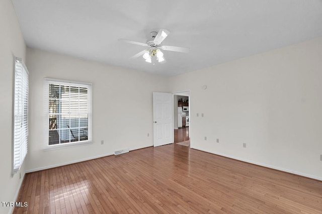 empty room with visible vents, baseboards, ceiling fan, and hardwood / wood-style floors