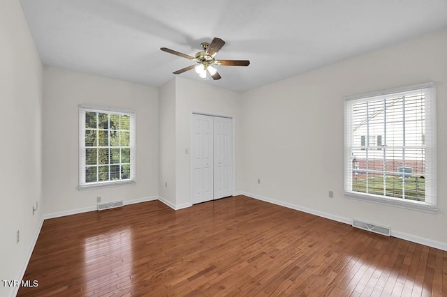 unfurnished bedroom with hardwood / wood-style flooring, baseboards, and visible vents