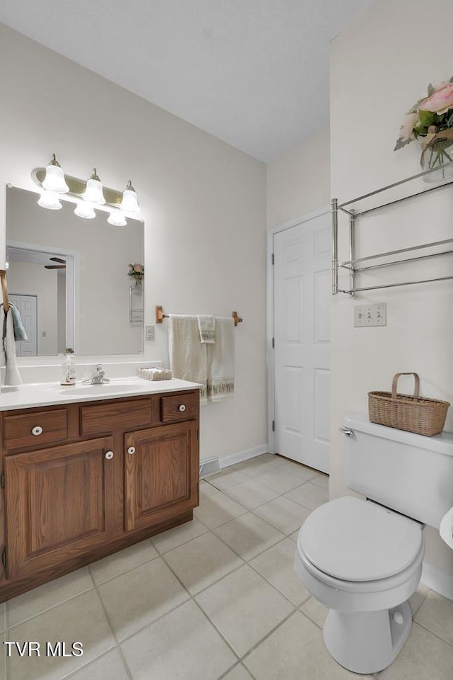 bathroom with baseboards, toilet, vanity, and tile patterned flooring