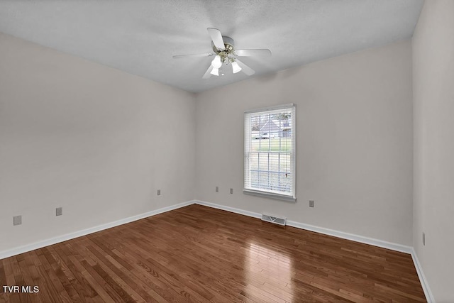 spare room with hardwood / wood-style floors, baseboards, visible vents, and ceiling fan