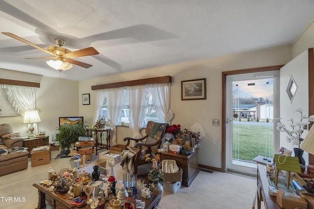 carpeted living area featuring a wealth of natural light, baseboards, and a ceiling fan