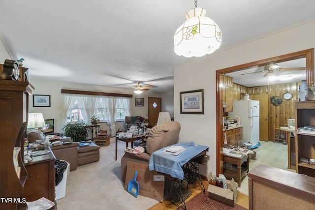 living area with tile patterned floors, ceiling fan, and wood walls