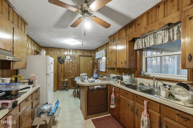 kitchen featuring a sink, light floors, dishwasher, and wooden walls