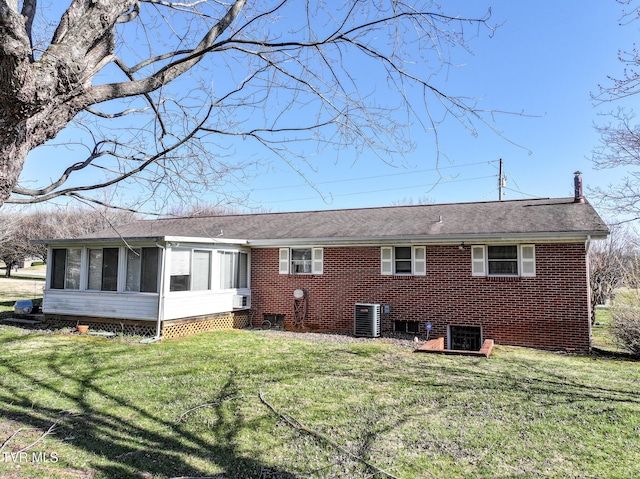 rear view of house featuring central AC unit, a lawn, and a sunroom