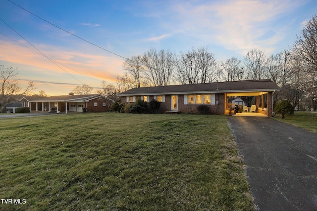 single story home featuring a carport, a yard, brick siding, and driveway