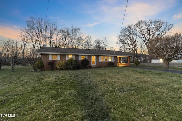 ranch-style home featuring brick siding, covered porch, and a front yard