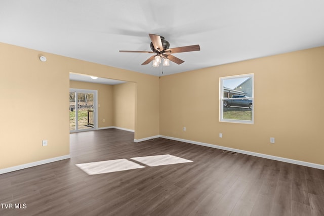 empty room with baseboards, dark wood-style floors, and a ceiling fan