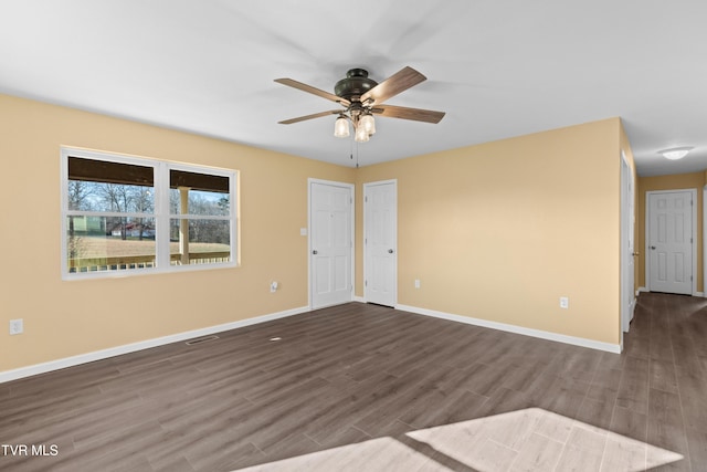 unfurnished room with visible vents, baseboards, wood finished floors, and a ceiling fan