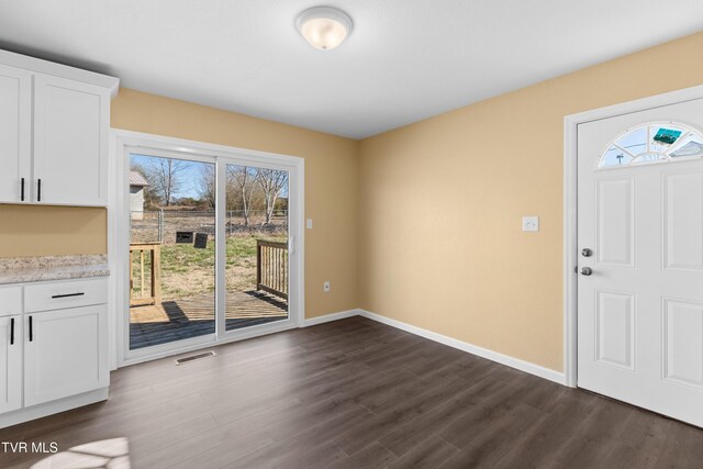 unfurnished dining area featuring a wealth of natural light, visible vents, dark wood finished floors, and baseboards