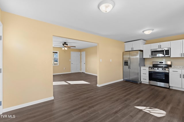 kitchen with dark wood-type flooring, baseboards, light countertops, appliances with stainless steel finishes, and white cabinetry