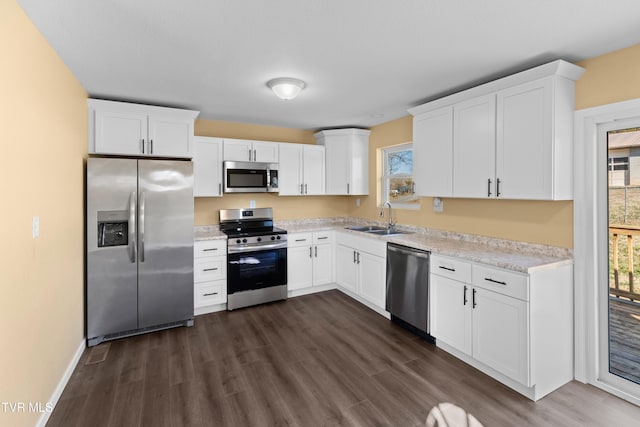 kitchen with dark wood-style floors, appliances with stainless steel finishes, white cabinetry, and a sink