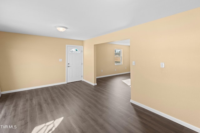 spare room with dark wood-type flooring and baseboards