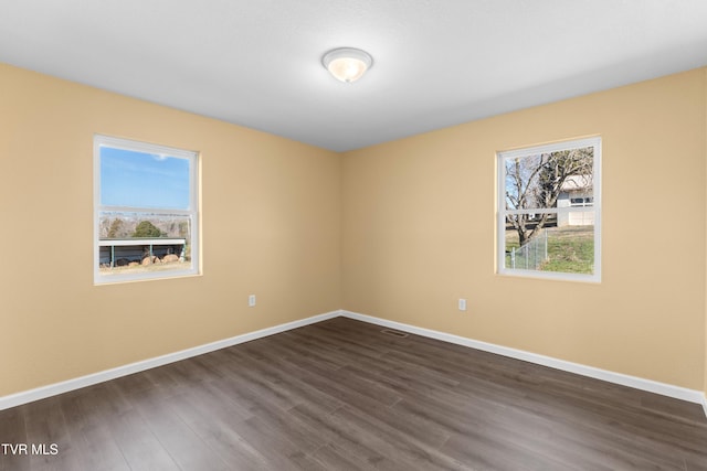 unfurnished room with visible vents, dark wood-type flooring, and baseboards