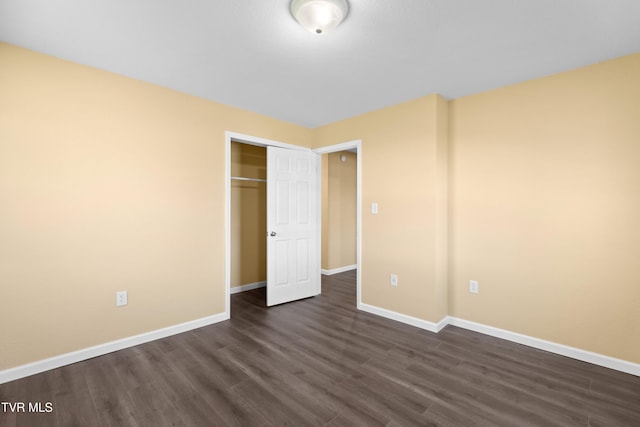 unfurnished bedroom featuring a closet, baseboards, and dark wood-style floors