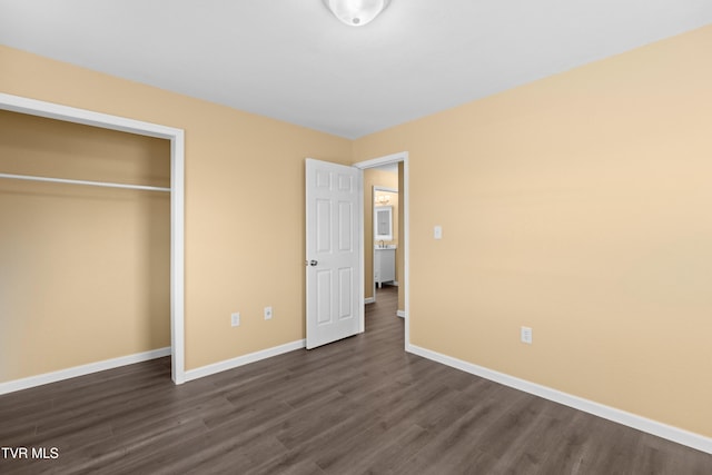 unfurnished bedroom with dark wood finished floors, a closet, and baseboards