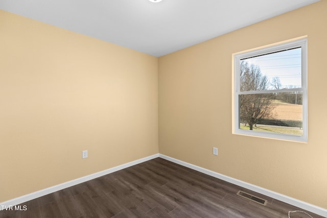 spare room with dark wood-style floors, baseboards, and visible vents