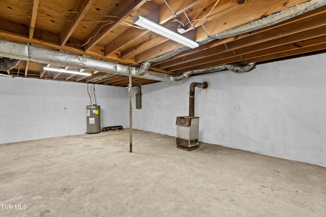 unfinished below grade area with electric water heater and a wood stove