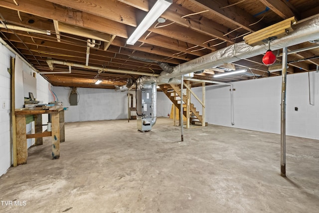 unfinished basement featuring heating unit and stairs