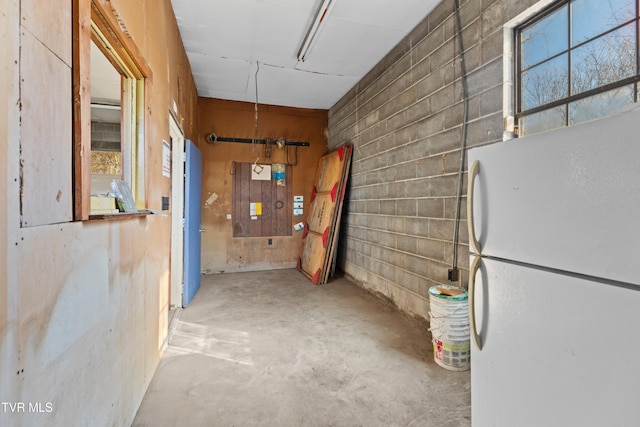 interior space with concrete block wall and freestanding refrigerator