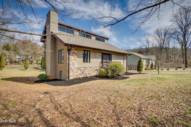 view of front of home featuring stone siding, a chimney, and a front lawn