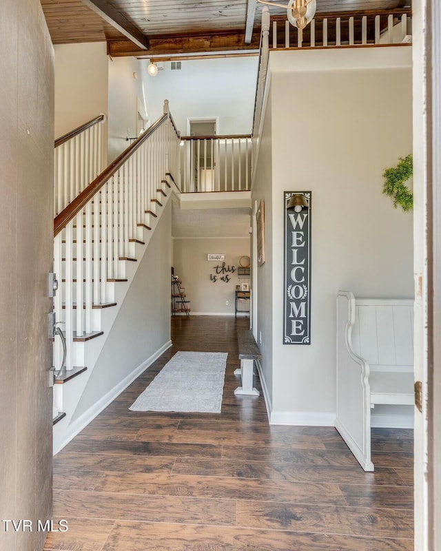 foyer with beam ceiling, stairway, a towering ceiling, and wood finished floors