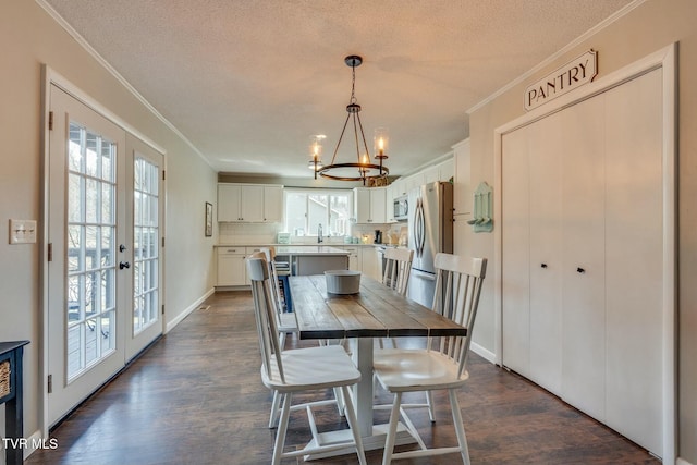 dining space featuring dark wood-style floors, a textured ceiling, an inviting chandelier, and ornamental molding