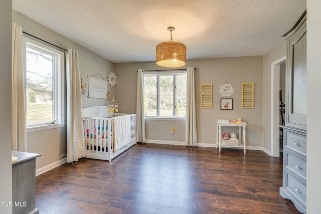 unfurnished bedroom featuring baseboards, a textured ceiling, and dark wood-style flooring