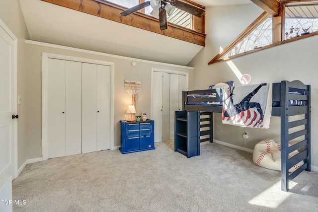 bedroom with baseboards, two closets, vaulted ceiling with beams, and carpet