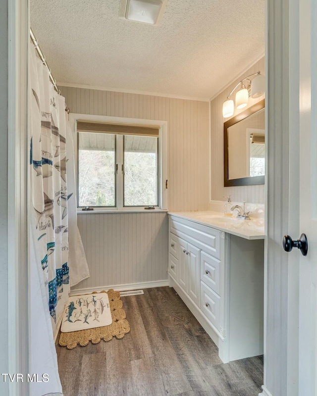 bathroom featuring vanity, ornamental molding, a shower with curtain, wood finished floors, and a textured ceiling