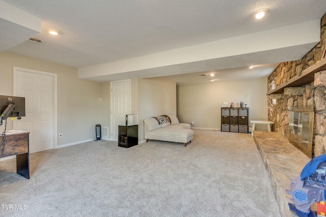 sitting room featuring a stone fireplace, carpet flooring, baseboards, and a textured ceiling