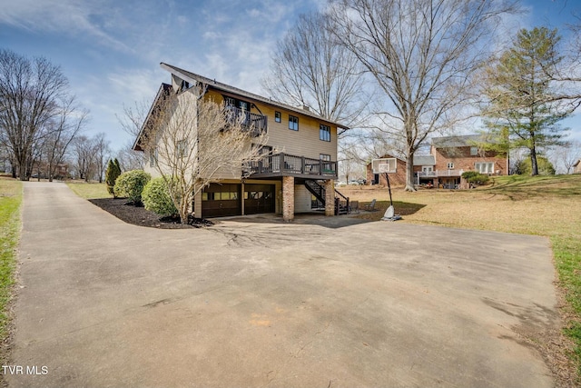 rear view of house featuring stairway, driveway, an attached garage, a yard, and a deck