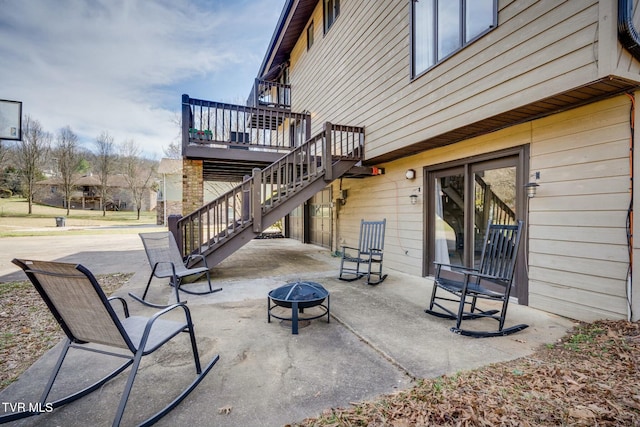 view of patio / terrace featuring stairway, a deck, and an outdoor fire pit