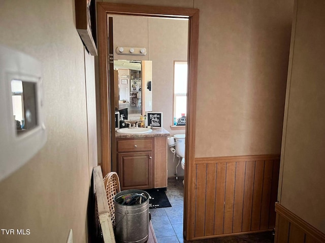 interior space with a sink, tile patterned flooring, and wainscoting