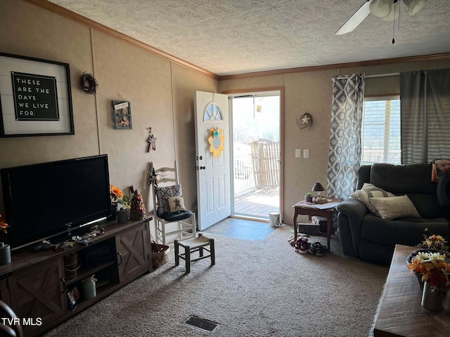 living area featuring a ceiling fan, carpet, crown molding, and a textured ceiling