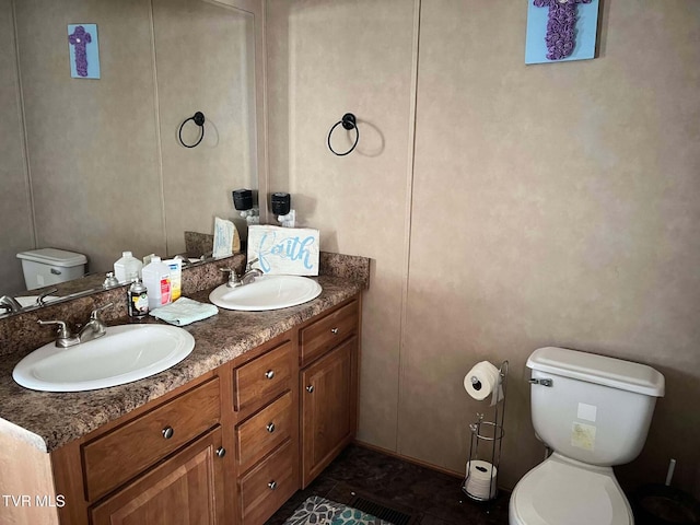 bathroom featuring double vanity, toilet, and a sink