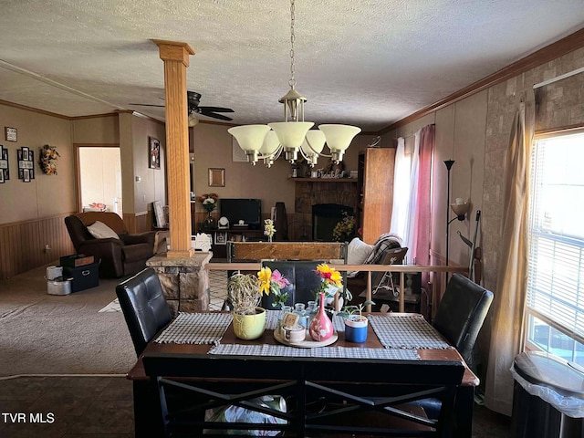 dining space featuring decorative columns, wood walls, carpet flooring, and crown molding