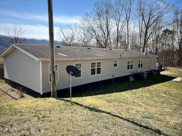 rear view of house with a lawn and central AC