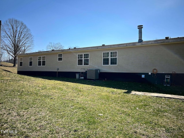 back of property featuring central air condition unit and a lawn