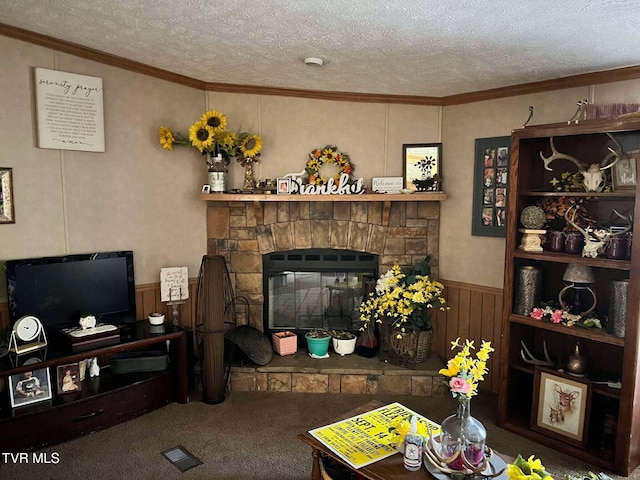 living room with a wainscoted wall, a textured ceiling, crown molding, and carpet