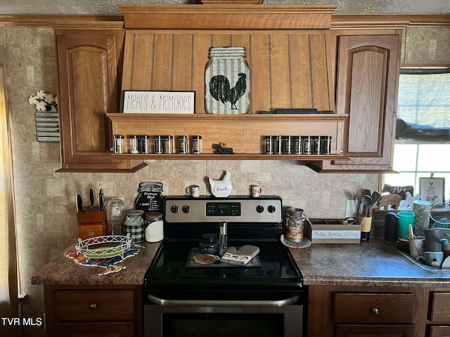 kitchen with dark countertops, brown cabinetry, stainless steel electric range, and backsplash