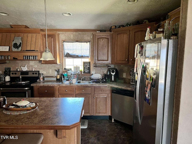 kitchen with a sink, appliances with stainless steel finishes, a textured ceiling, decorative light fixtures, and backsplash