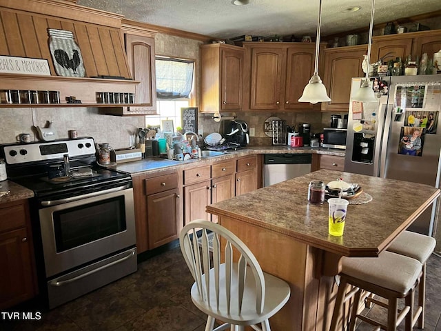 kitchen with a sink, a textured ceiling, backsplash, stainless steel appliances, and a breakfast bar area