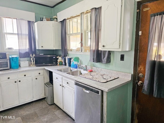 kitchen featuring a sink, light countertops, white cabinets, appliances with stainless steel finishes, and stone finish flooring