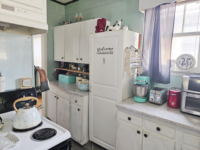 kitchen featuring white cabinetry, light countertops, under cabinet range hood, and electric range oven