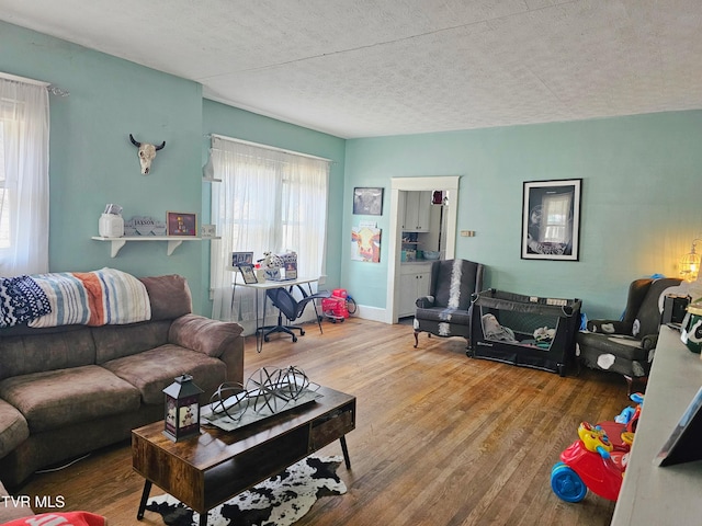 living area with a textured ceiling, baseboards, and wood finished floors