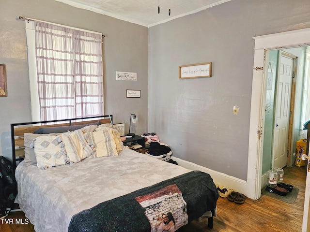 bedroom featuring baseboards, wood finished floors, and ornamental molding