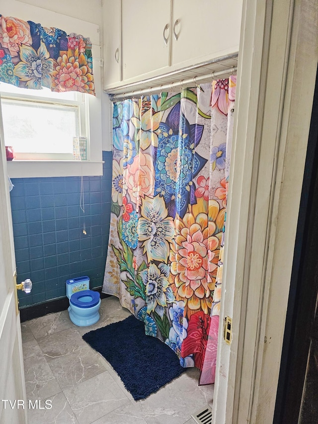 full bath with tile walls and a shower with curtain