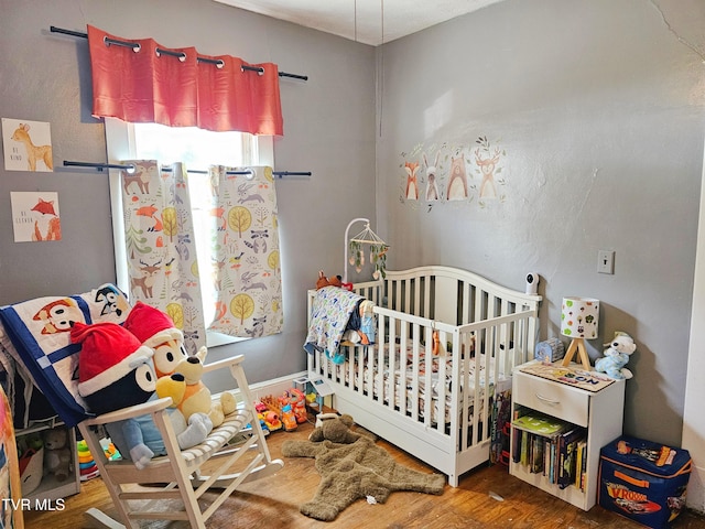 bedroom featuring a crib and wood finished floors