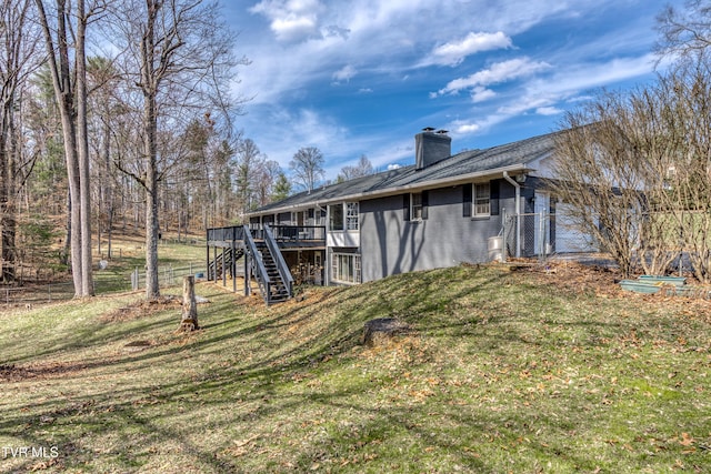 rear view of house with a lawn, a deck, fence, stairway, and a chimney